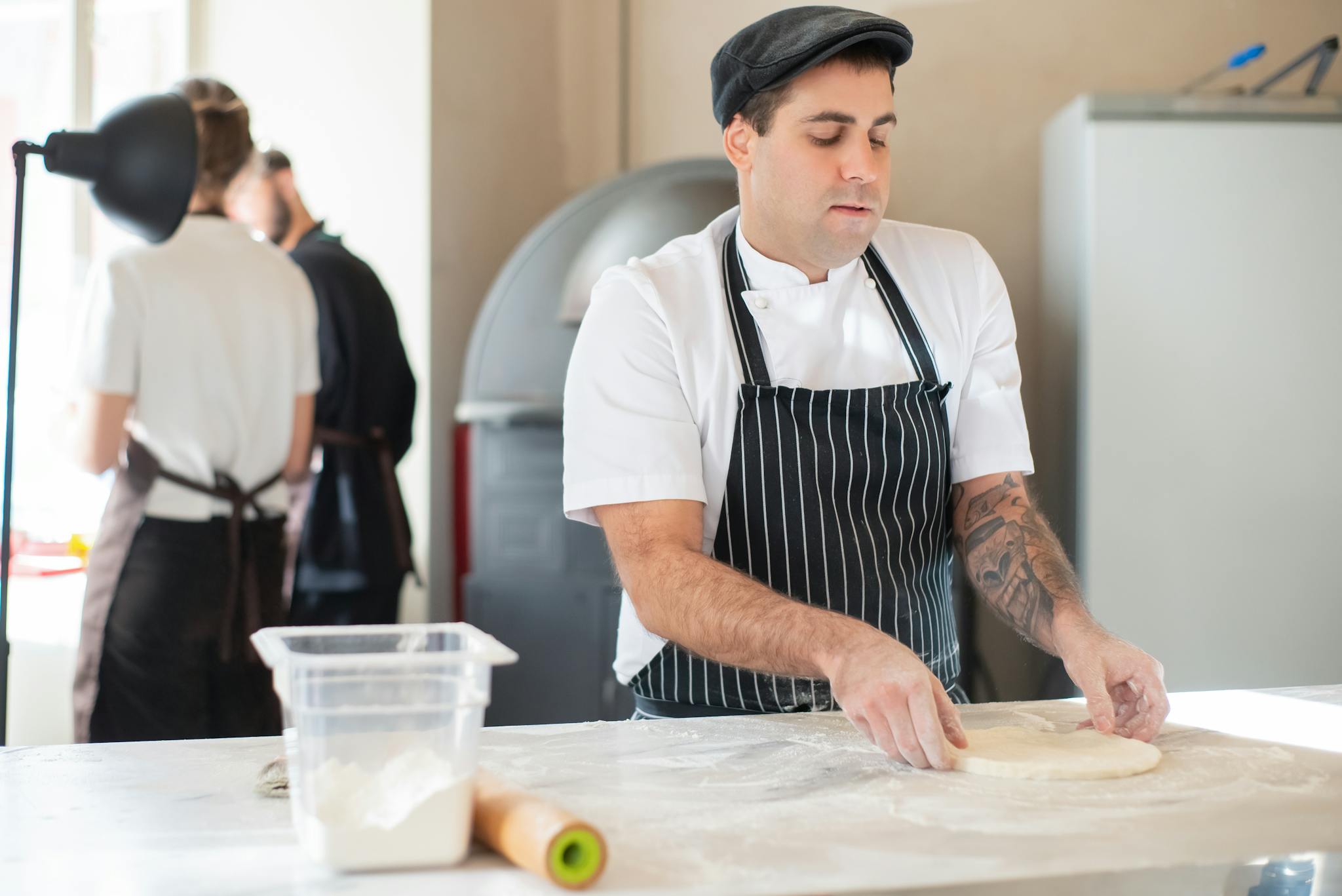 Chef in striped apron skillfully prepares dough at a cafe counter, Portugal.